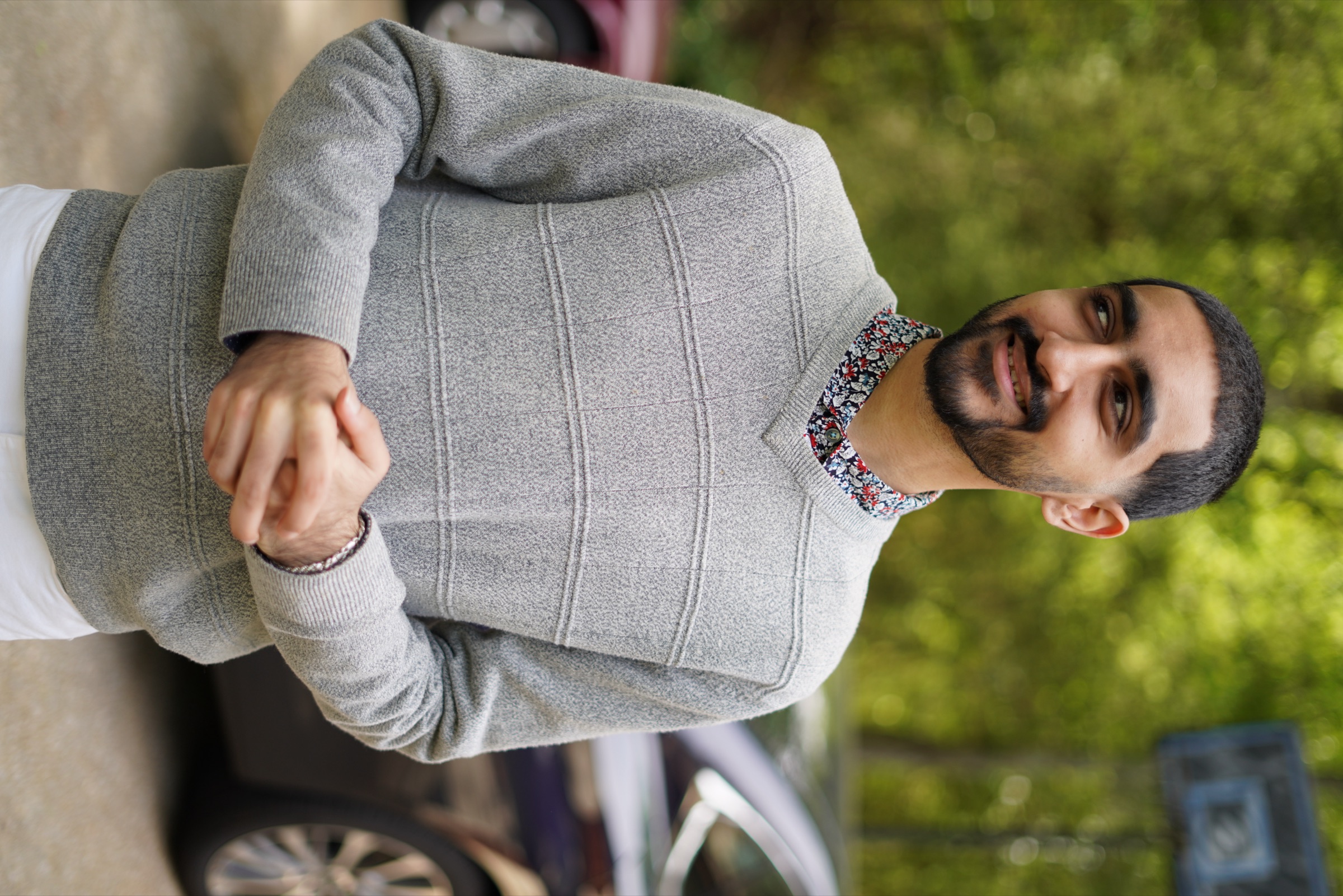 Young man in a grey sweater laughing off-camera in natural light