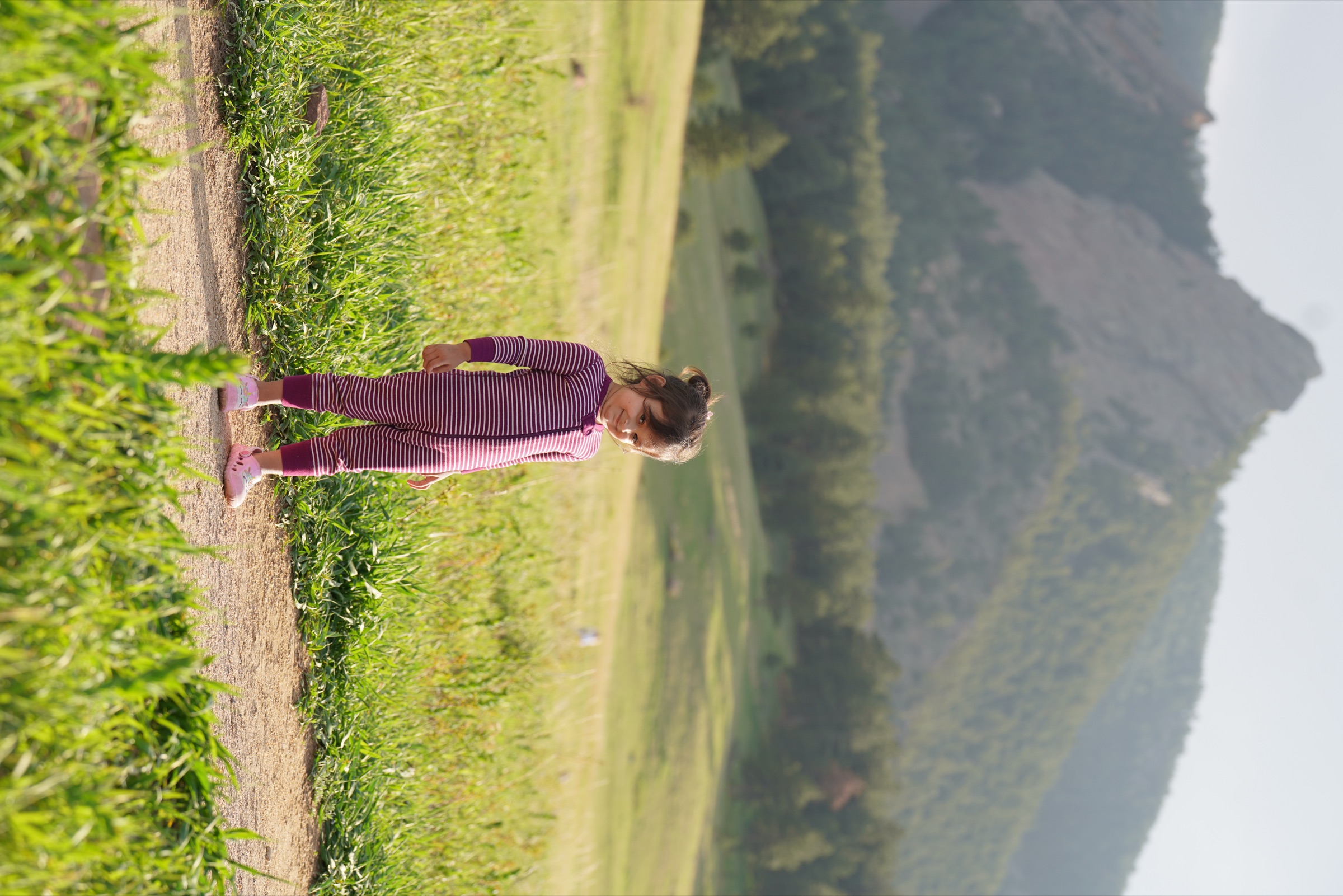 Girl in striped onesie on a trail beneath the Boulder Flatirons