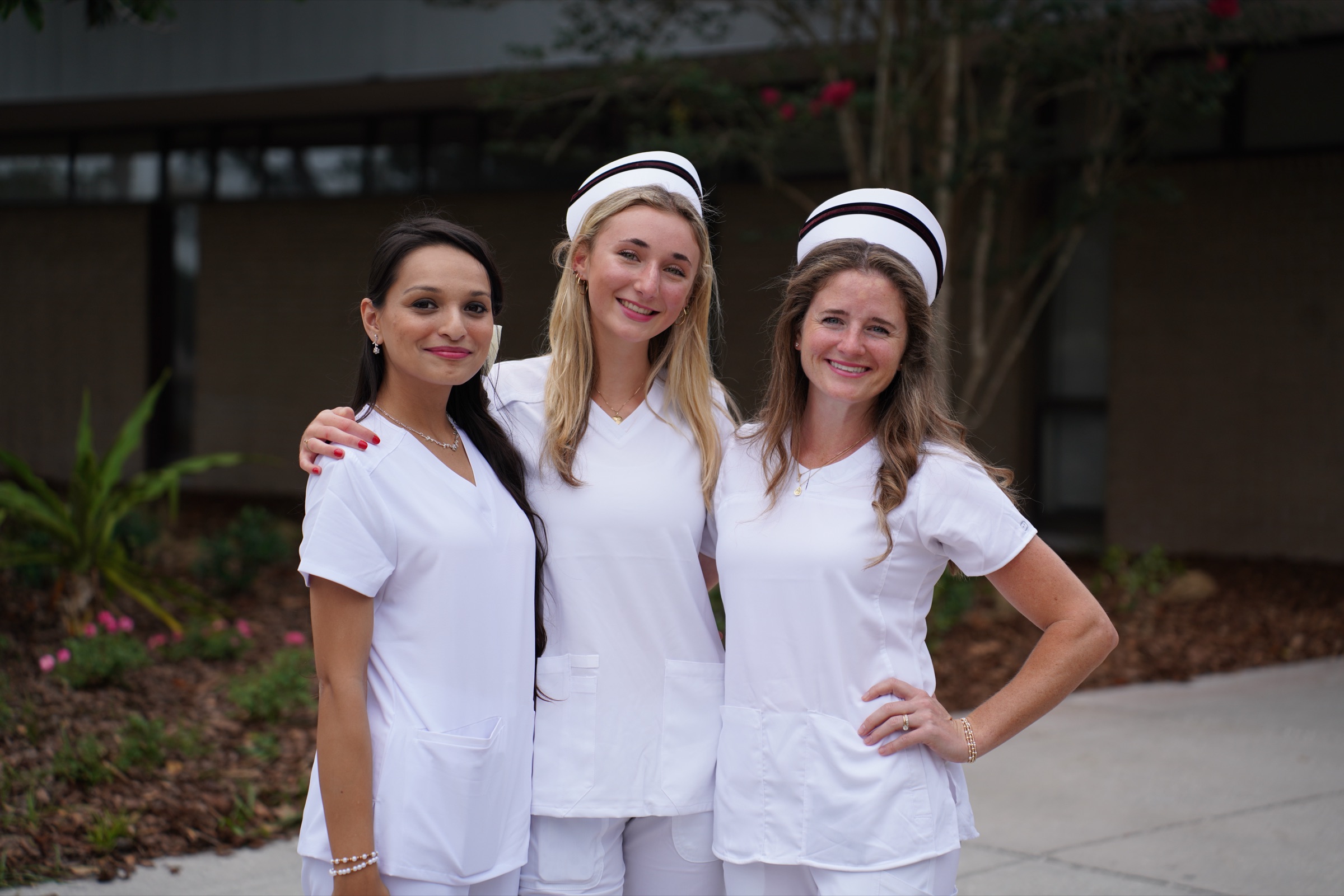 Three nurses in whites celebrating at their pinning ceremony