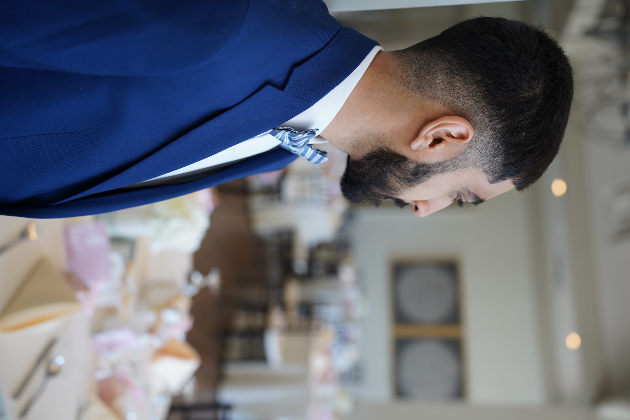 Groom in a blue suit looking over the reception room