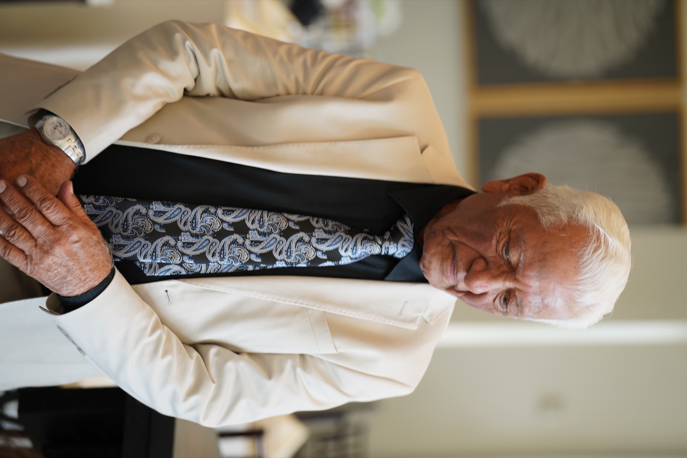 Elegant older gentleman in a cream jacket, caught in a quiet moment