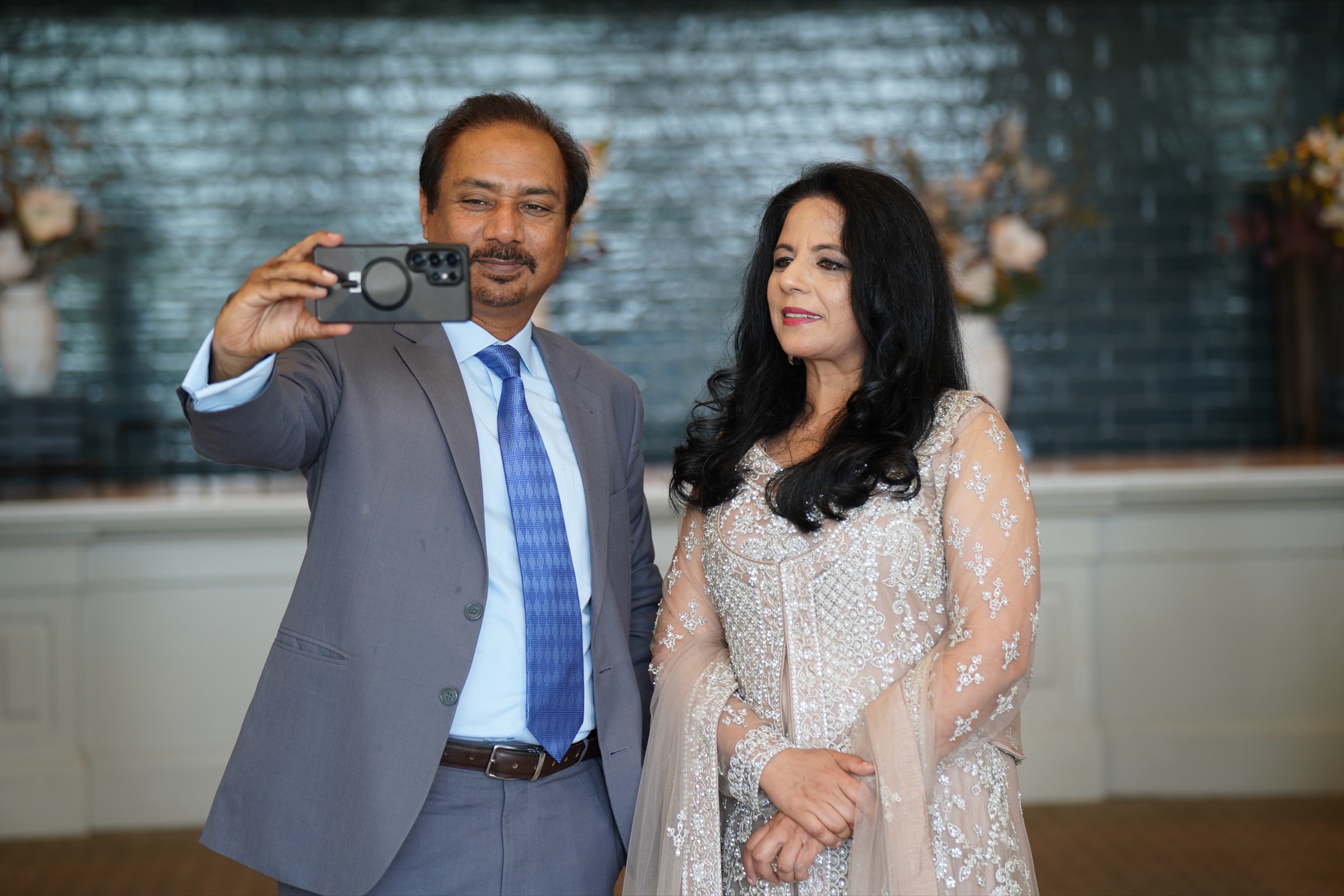 Couple taking a selfie in front of the reception wall