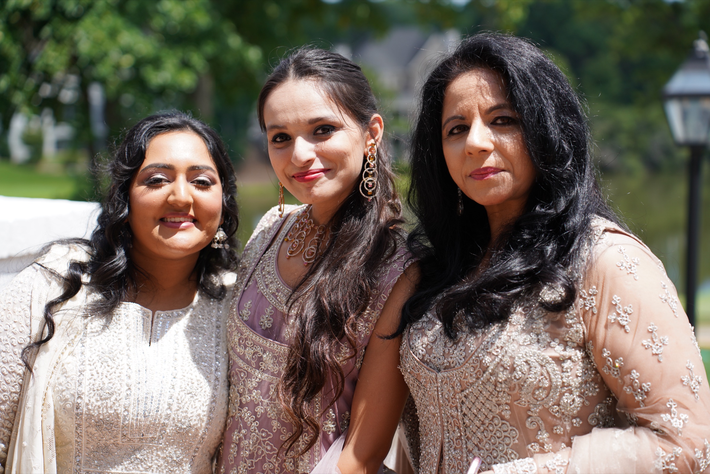 Three women in embroidered formal dresses in the summer sun