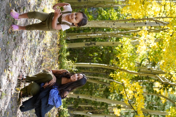 Girl bolting away while mom laughs behind her in an aspen grove